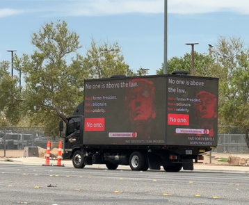 mobile billboard circles Las Vegas Trump rally.